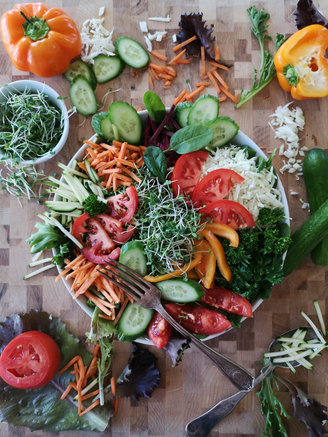 Colorful salad bowl with fresh vegetables and vintage utensils.