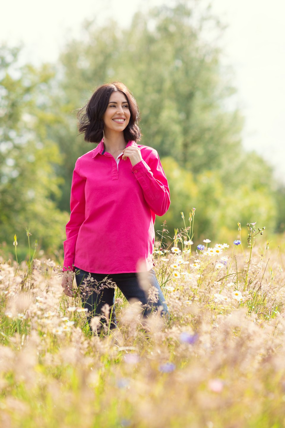 Woman in a pink shirt smiling in a wildflower field.